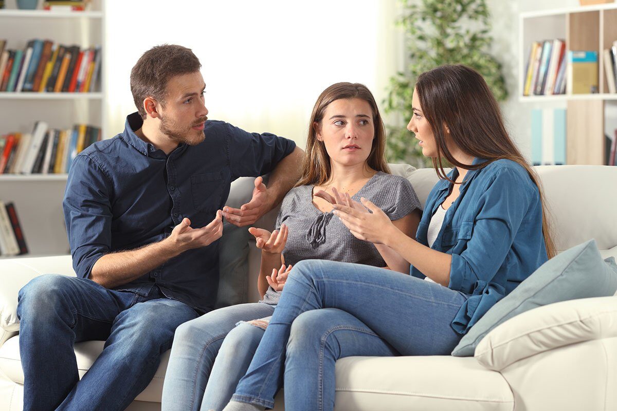 Three family members talking about family assets sitting on a couch at home