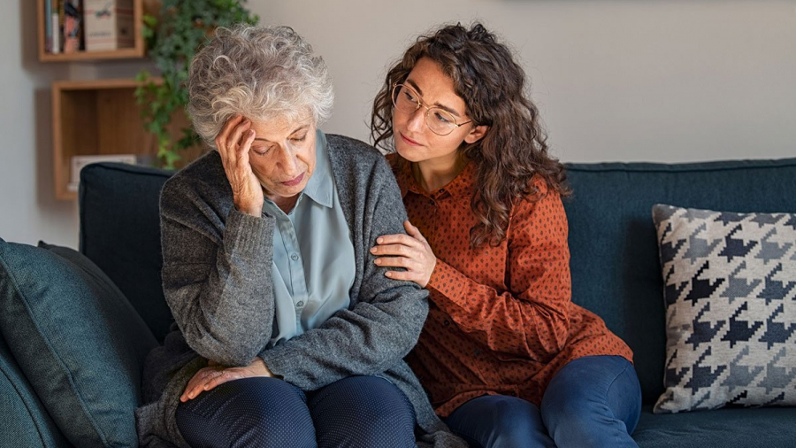Young woman consoling her elderly mother dealing with Alzheimer's disease.