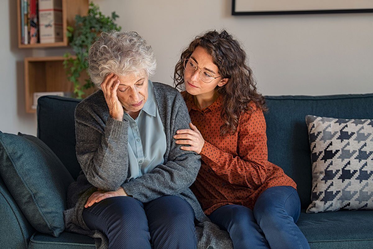 Young woman consoling her elderly mother dealing with Alzheimer's disease.