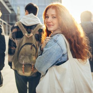 Female student glancing back while going for a class in college. Girl walking with friends going for class in high school.