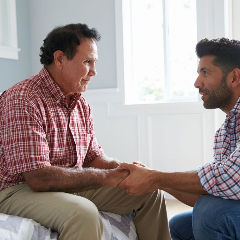 Adult Son Comforting Father Suffering With Dementia