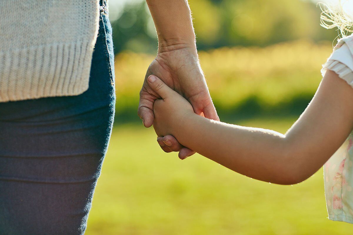 Cropped shot of a little girl holding an unrecognizable woman’s hand in the park