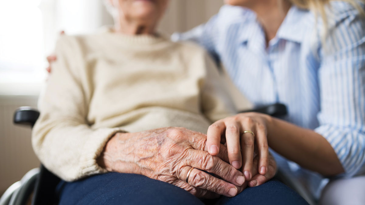 Adult woman holding hand of elder woman